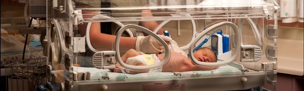Technician with infant in neonatal crib